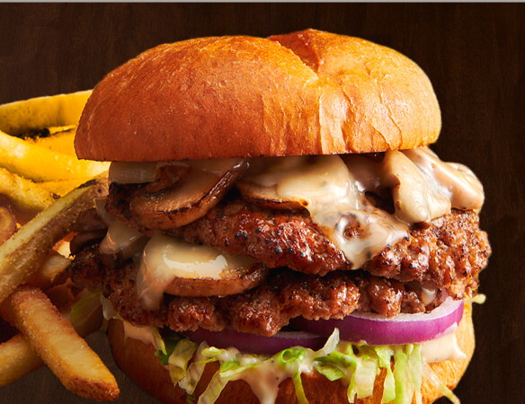 $8.99 Mushroom Swiss Smashed Burger  Two smashed beef patties topped with Swiss cheese, roasted mushrooms, Caesar dressing, lettuce, and onion. Served with fries or tots.